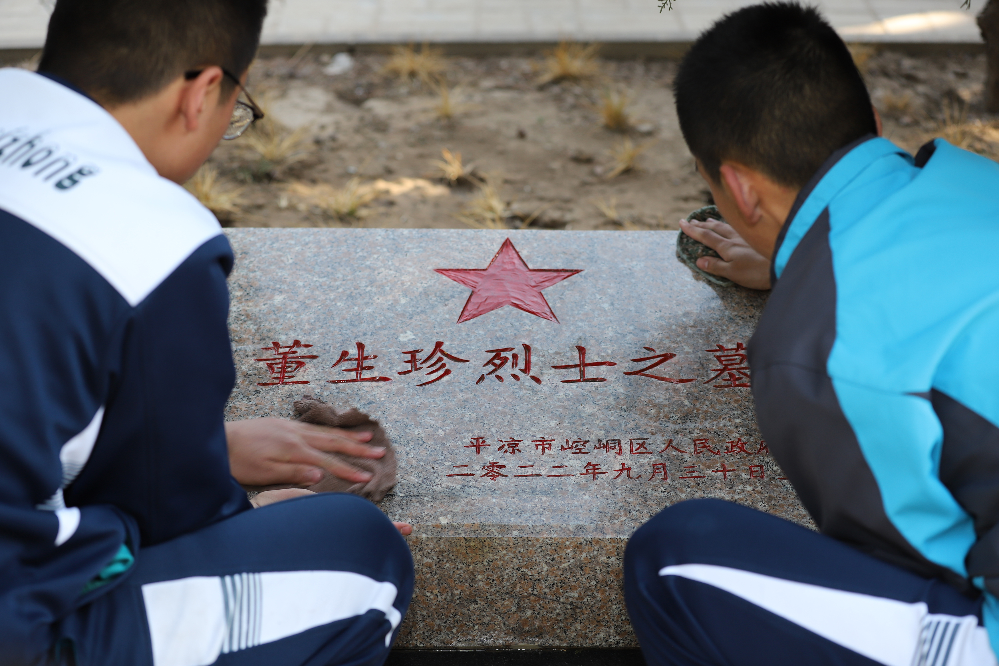 08——3月29日，甘肅省平?jīng)鍪械谒闹袑W學生在平?jīng)鍪辛沂苛陥@擦拭烈士墓碑。.JPG