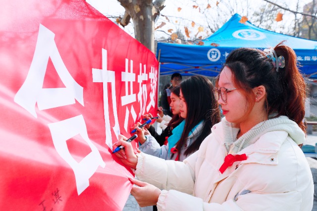 20231127中國石油大學（華東）青年學子在合力共抗艾滋的條幅上簽字，表達抗擊艾滋病的決心和信心  .jpg