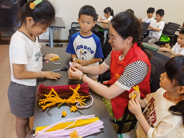 7月12日，在泰州市海陵區(qū)城東街道林湖社區(qū)，泰州市大浦小學(xué)“綠葉”暑期公益班的老師正在教孩子們一起做手工2（拍攝者：泰州市大浦中心小學(xué)  陳惠婷）.jpg